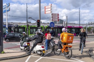 Cyclist, moped rider, waiting at a red traffic light, Feijenoord, in front of the Erasmus Bridge,