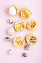 Raw uncooked tagliatelle pasta with quail eggs on a pink pastel background. top view, copy space