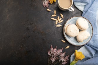 Meringues cakes with cup of coffee on a black concrete background and blue linen textile. Top view,