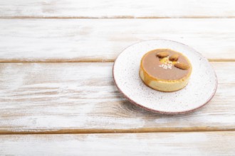 Sweet tartlets with almonds and caramel cream on a white wooden background. side view, copy space