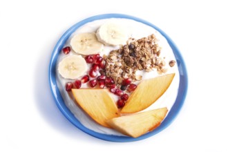 A blue plate with greek yogurt, granola, persimmon, banana, pomegranate isolated on white