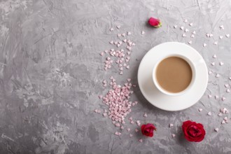 Red rose flowers and a cup of coffee on a gray concrete background. Morninig, spring, fashion