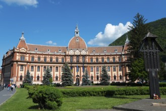 Majestic Renaissance building with tower surrounded by manicured greenery and clear skies