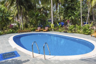 Swimming pool in tropical resort with small garden