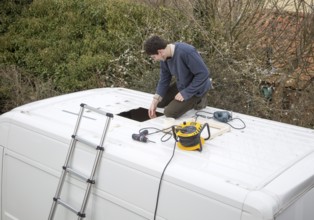 Cutting through roof of white metal camper van conversion to install ventilation window, UK