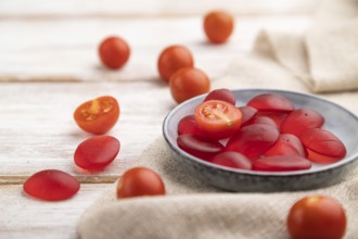 Jelly tomato candies on white wooden background and linen textile. close up, side view, selective