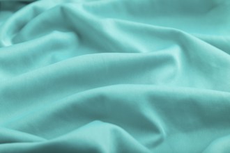 Fragment of silk blue tissue. Side view, natural textile background and texture. wave concept,