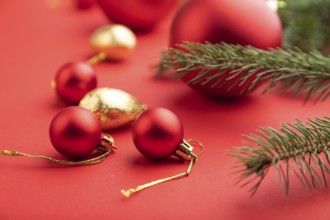 Christmas or New Year composition. Decorations, red balls, fir and spruce branches, on a red paper