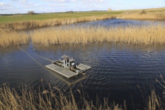 Water pump for irrigation system floating in pool, Bawdsey, Suffolk, England, UK