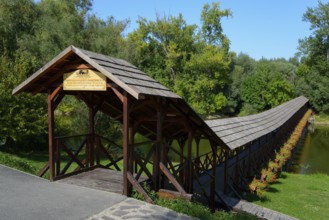 A covered wooden bridge spans a calm river on a sunny day with a clear blue sky at the ship mill,