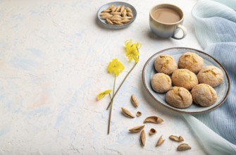 Almond cookies and a cup of coffee on a white concrete background and blue linen textile. Side