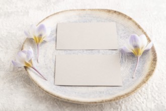 Gray paper invitation card, mockup with crocus flowers on ceramic plate and gray concrete