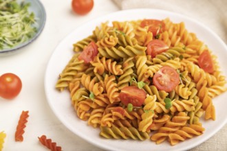 Tortiglioni semolina pasta with tomato and microgreen sprouts on a white wooden background and