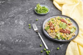 Quinoa porridge with green pea, corn and dried tomatoes on ceramic plate on a gray concrete