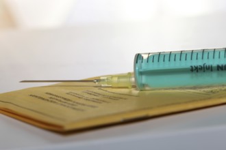 Symbolic image of vaccine with vaccination card and syringe