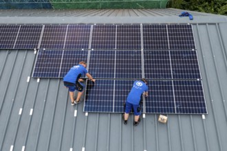 Installation of solar modules on the roof of a barn on a farm, over 240 photovoltaic modules are