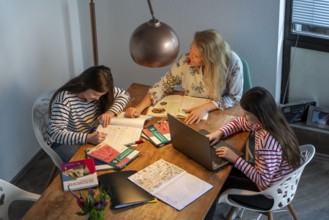 Homeschooling, during the lockdown in January 2021, mother helps her two daughters, at home,