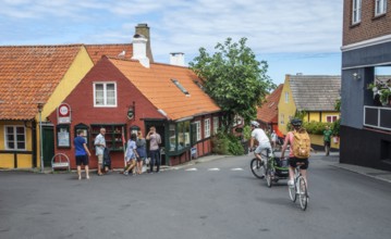 Cyclists on a street and at typical colored houses in Gudhjem, Bornholm, Baltic Sea, Denmark,