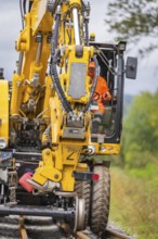 Heavy construction machine with hydraulic arm carries out track work, track construction, Hermann