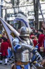 Procession of historically costumed guildsmen, man in knight's armour carrying flag, Great Almighty