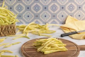 A pile of yellow beans on a wooden chopping board with a knife on the side