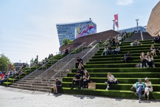 People sitting and relaxing on leafy steps in sunny weather, Liverpool