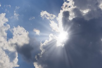 Rain clouds with sun shining through, rays of sunshine, blue sky