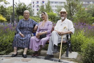 Three elderly Uyghurs sitting on a park bench in the city Hami, Kumul, one of China's ethnic