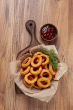 Deep fried onion rings, appetizer, with tomato sauce, on a wooden table, no people, favorite dish