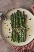 Grilled asparagus, spices and herbs, parmesan cheese, on a beige plate, top view, rustic, no people