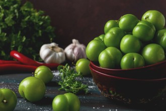 Tkemali, green cherry plum, with ingredients for sauce, cilantro, mint, hot pepper, garlic, on a