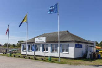 Small historic building with waving flags under a blue sky in sunny weather, Rügen, Hiddensee