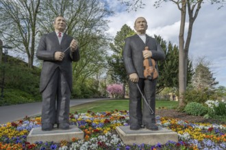 Statues of two men, one with a violin, the other with a conductor's baton, stand in a colourful