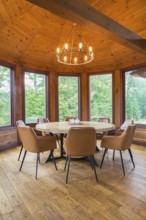 Round wooden dining table with tan leather armchairs in dining room inside a milled Eastern white