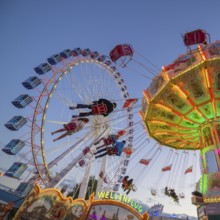 A funfair at dusk with illuminated chain carousel and Ferris wheel, Europa Rad, rides, wave flight,