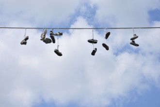 Shoes hanging on a wire against a blue sky with scattered clouds, Bad Mergentheim,