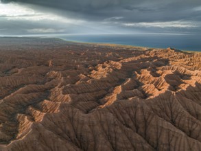 Landscape of eroded hills, badlands at sunset, Issyk Kul Lake in the background, aerial view,