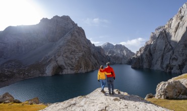 Couple at the blue mountain lake between rocky steep mountain peaks, Kol Suu Lake, Sary Beles