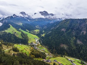 The village of Tiers, in the background the peaks of the rose garden, shrouded in mist, drone shot,