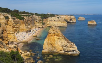 Coastal landscape with rocky cliffs and a beach on the clear blue ocean under a sunny sky, Praia da