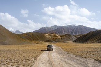 Nature tourism, road trip, overlander, off-road vehicle on a gravel road in the Pamir Mountains,