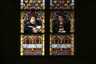 Colourful stained glass window with reformers Martin Luther with quill and Bible and Philipp