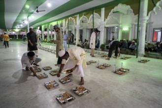 Volunteers distribute and arrange rows of 'iftar' meal for devotees to break their fast, during the