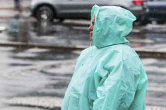 A man with a rain cape stands on a street in heavy rainfall, Berlin, 22/06/2024, Berlin, Berlin,