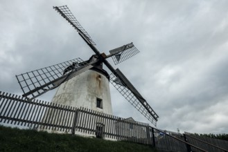 Large historic windmill under a cloudy sky, wooden fence, Podersdorf, Burgenland, Austria, Europe