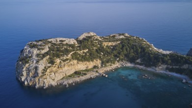 Drone shot, Dense vegetation covers a rocky island surrounded by crystal clear sea, Anthony Quinn