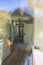 Corridor view with doors and windows, reflection of nature visible in the glass, refugee