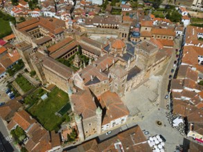 Aerial view of an old monastery with red roofs and village square, surrounded by historic buildings