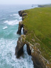 Steep coastline with characteristic rock arches and thundering waves crashing against the rocks,