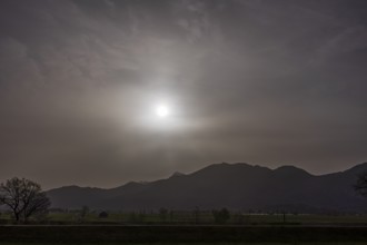 Sahara dust covers the sun in front of a mountain landscape, spring, Loisach-Lake Kochel-Moore,